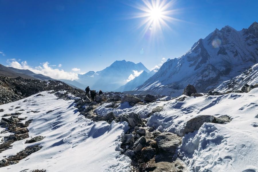 Trekkers hiking on snowy mountain trail in the Himalayas